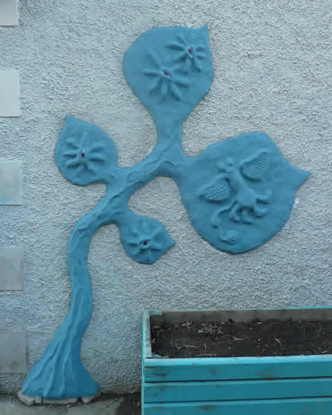 Cob mural of a blue imaginary tree with flowers and strange insect
